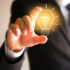 Hand holding a glowing lightbulb, symbolizing an idea or resource